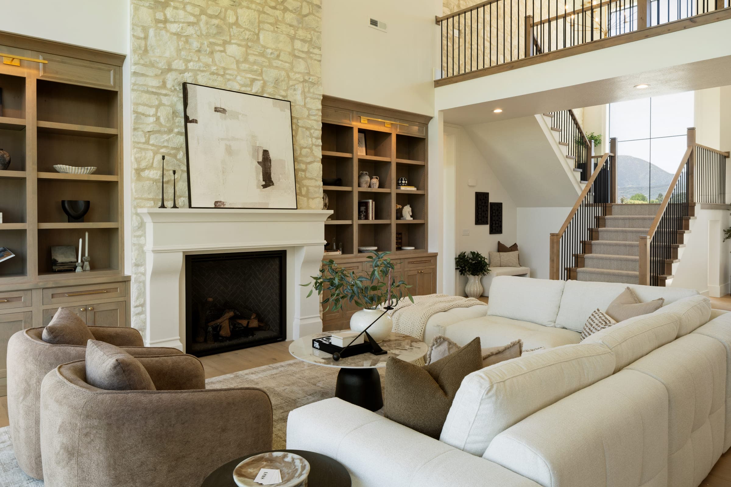 Two-storey living room staged by SWAY around a limestone fireplace framed by full-height built-ins.